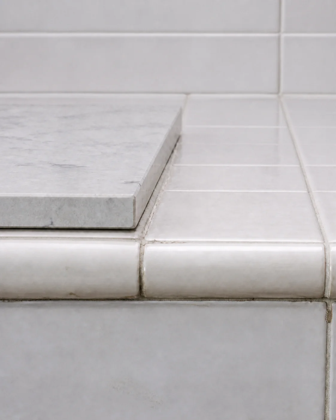Close-up comparison showing the height difference between an old tiled countertop edge and a new stone slab edge