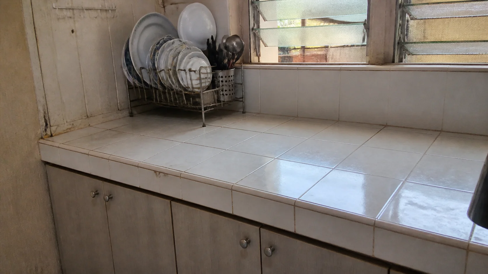 Old tiled kitchen countertop in a Malaysian home before renovation, showing visible grout lines and wear
