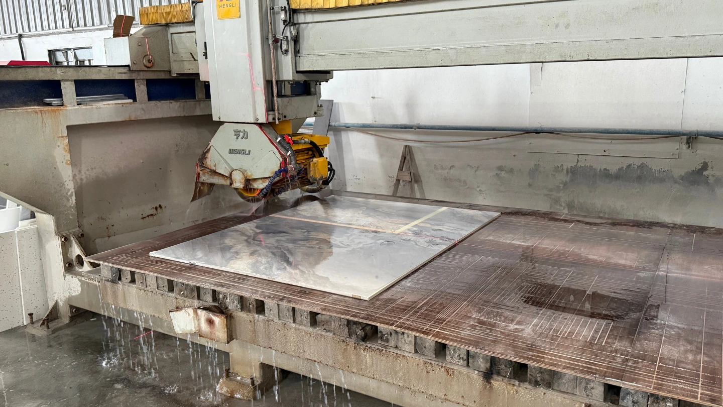 Stone fabricator operating a bridge saw machine to cut a quartz countertop slab in a Malaysian workshop Stone fabricator operating a bridge saw machine to cut a quartz countertop slab in a Malaysian workshop